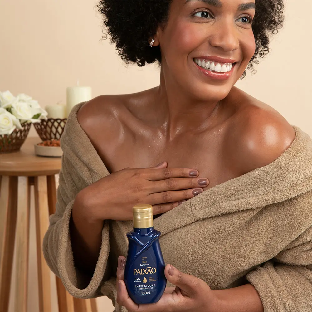 mulher negra com frasco do óleo corporal paixão