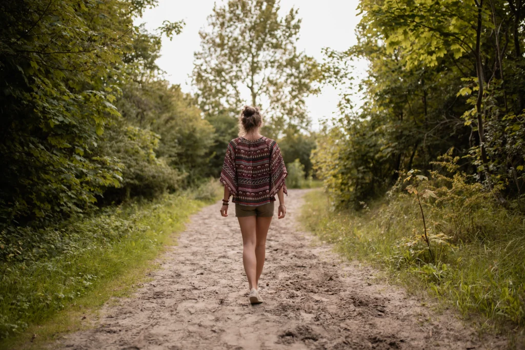 Mulher andando por caminho de área verde, floresta